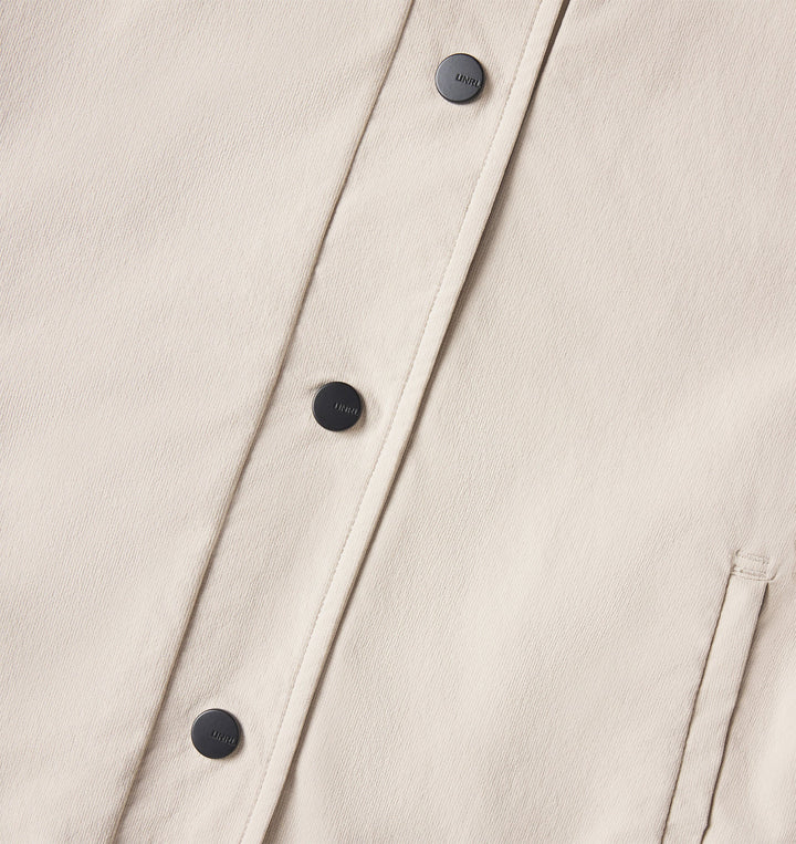 Close-up of a beige jacket with black buttons on a light gray background