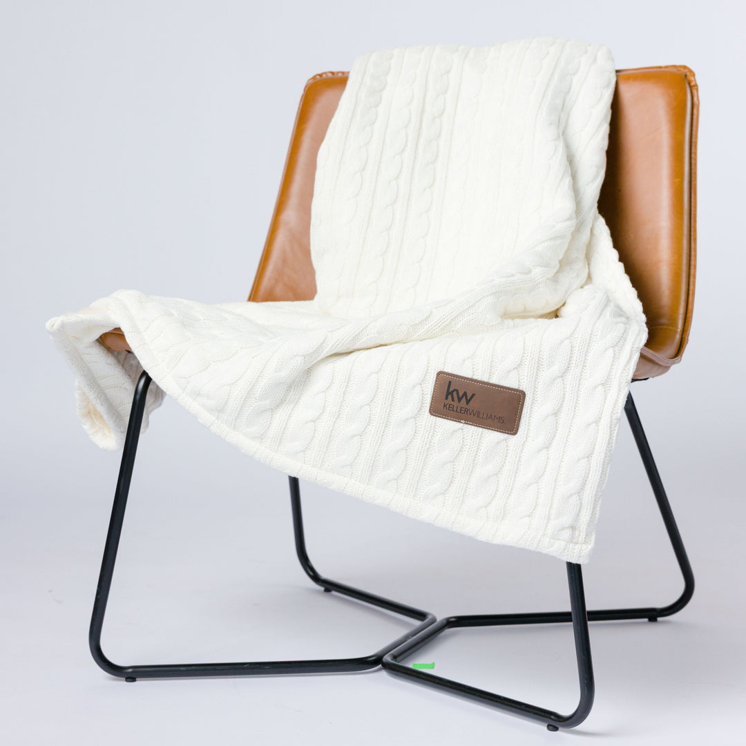 White textured blanket draped over a brown chair on a white background
