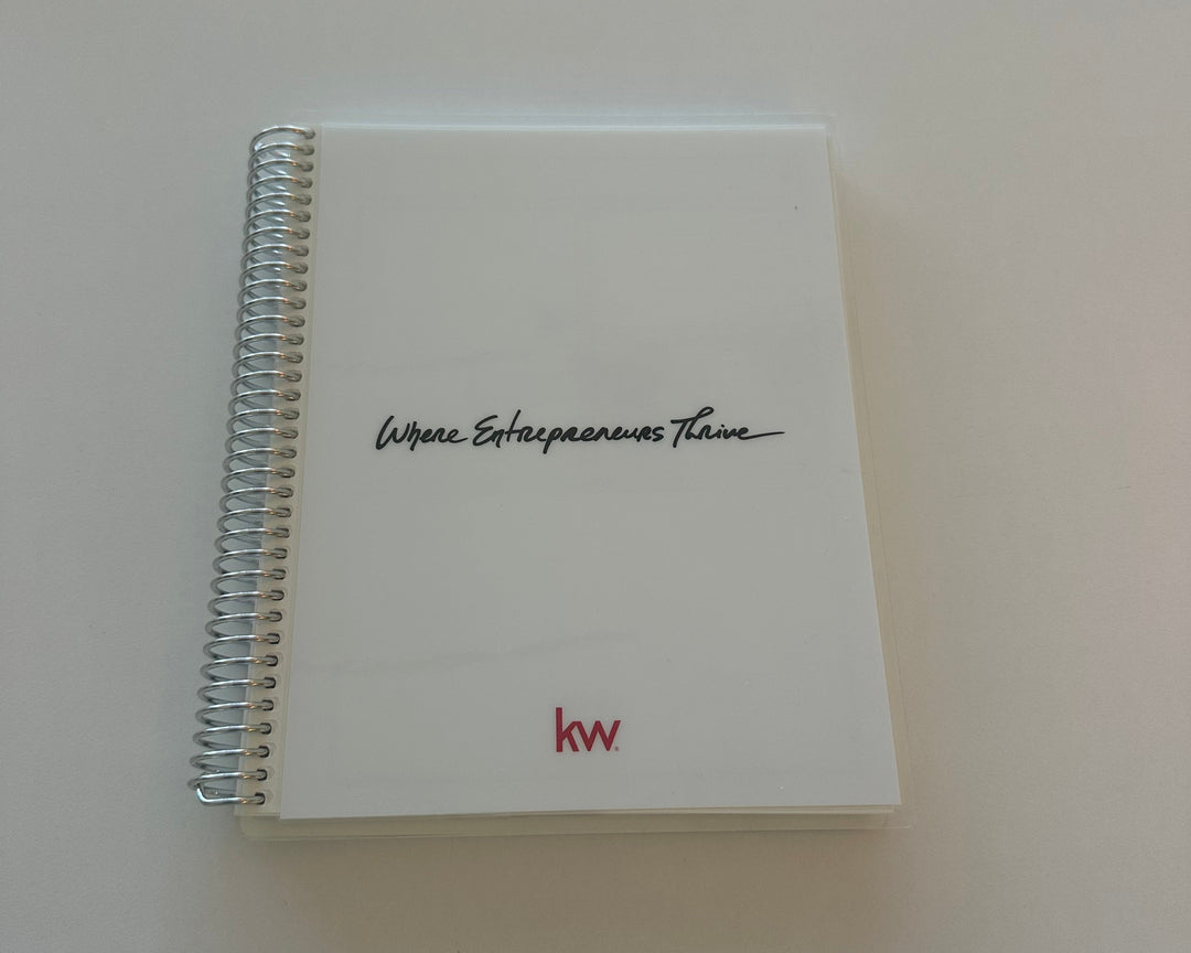 Small spiral-bound notebook with handwritten text on a plain background