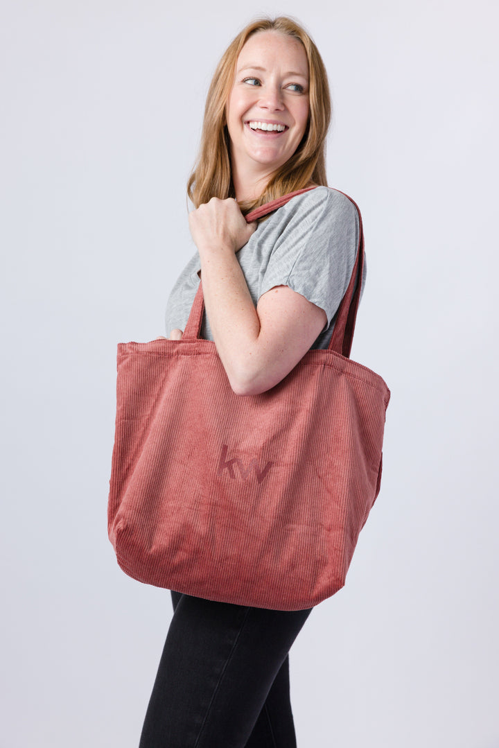Woman holding a red tote bag against a white background