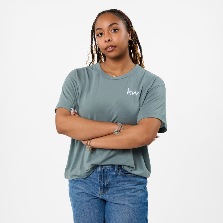 Person wearing a green t-shirt with a logo on a white background