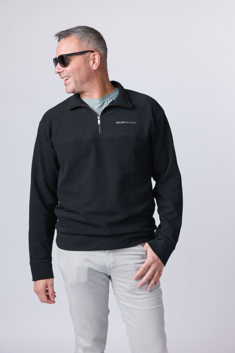 Man wearing a black quarter-zip sweatshirt with a logo on a white background