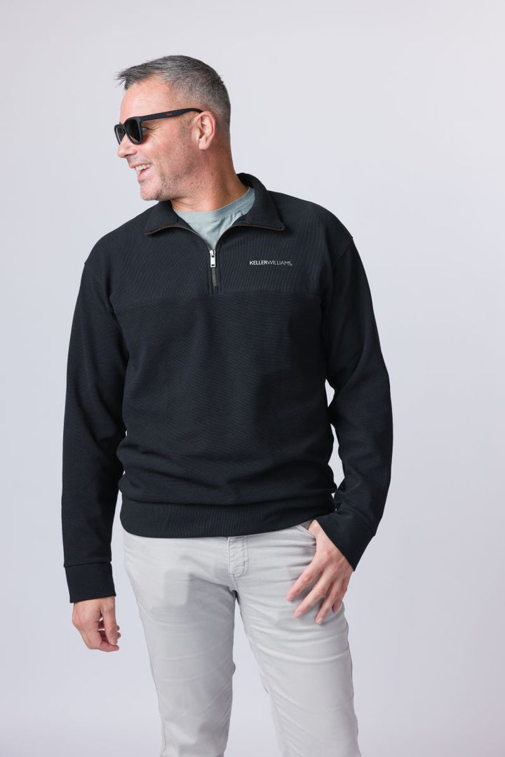 Man wearing a black quarter-zip sweatshirt with a logo on a white background