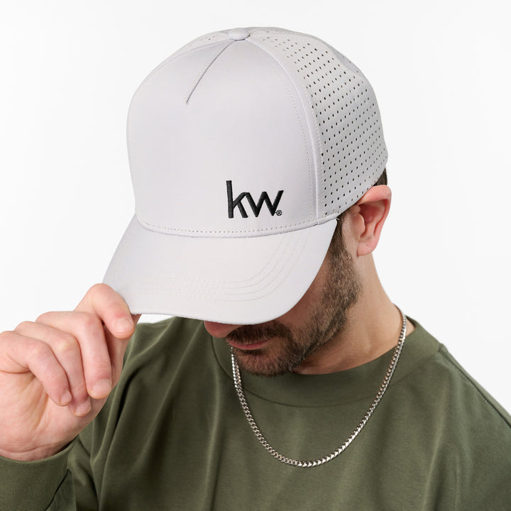 Person wearing a white cap with 'kw' logo on a white background